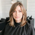 Femme aux cheveux fins coiffée d'un carré dégradé effilé tombant sur les épaules dans un salon de coiffure moderne