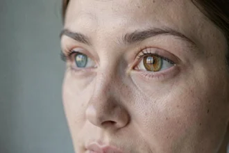Gros plan sur les yeux d'une femme montrant la nuance centrale ambrée et le contour bleu-vert de l'iris